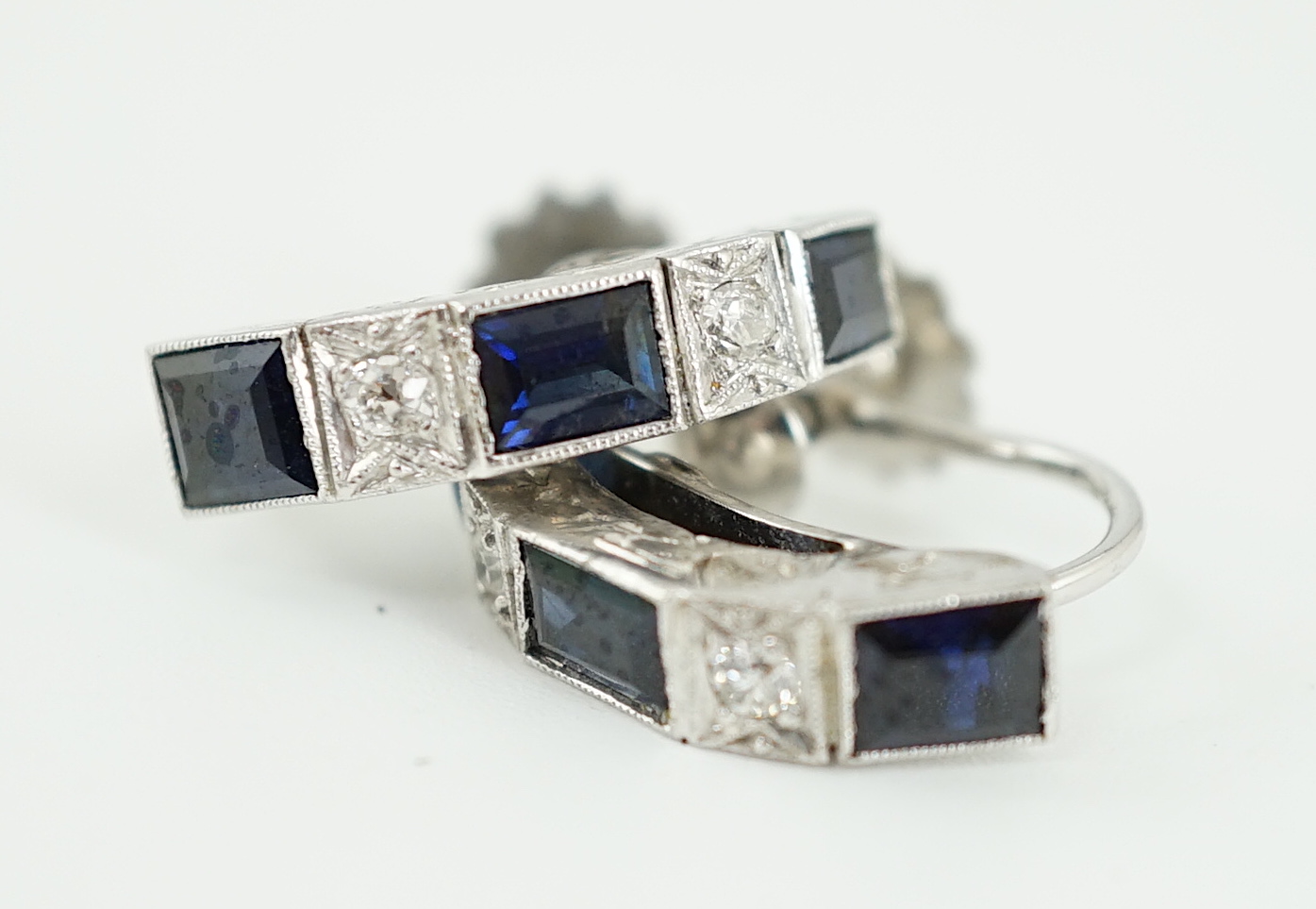 A pair of 9ct white gold, three stone sapphire and two stone diamond set half hoop ear clips, 16mm, gross weight 4.1 grams.